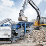 Kleemann MOBIREX MR 130i EVO2 im Einsatz mit dem John Deere Bagger 345GLE beim Betonrecycling in Kalifornien